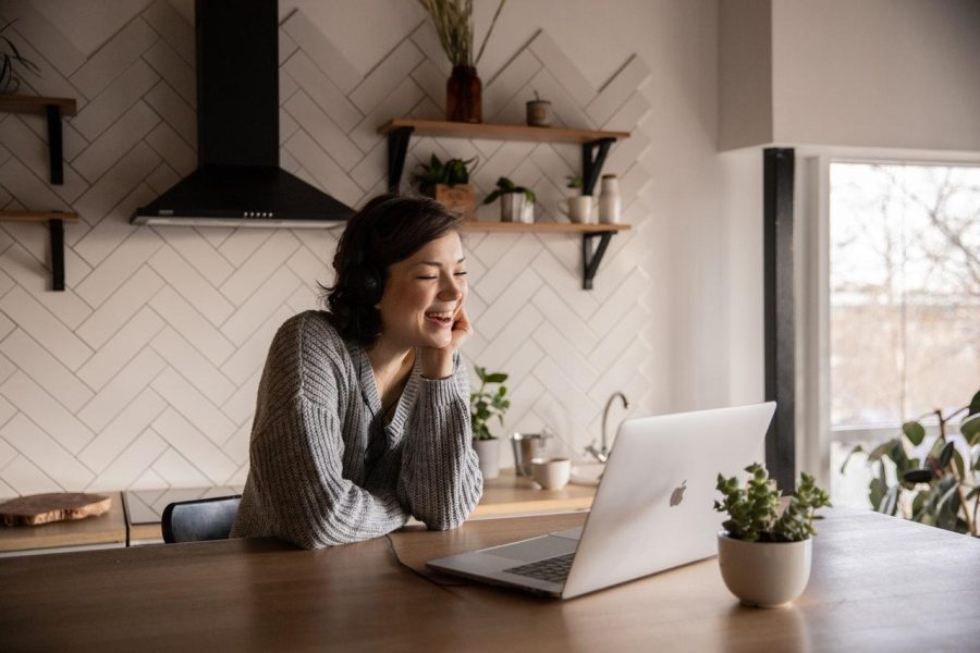 Women laughing at a table with a laptop